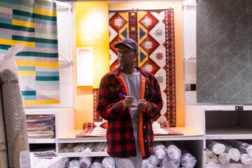 Black ethnic man shopping in a carpet supermarket, with shopping list