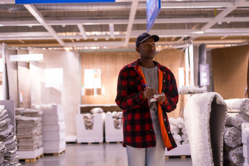 Black ethnic man shopping in a carpet supermarket, buying prices