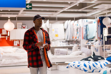 Black ethnic man shopping in a supermarket for almeadas and cushions. with the shopping list