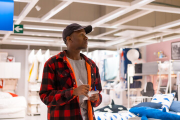Obraz premium Black ethnic man shopping in a supermarket for almeadas and cushions. comparing prices