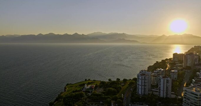 Antalya Turkey Aerial v20 flyover coastal park at fener neighborhood, sun setting behind the mountain with beautiful golden sunset reflection on mediterranean sea - Shot with Mavic 3 Cine - July 2022