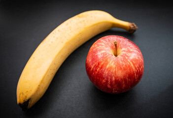 Fresh red apple and banana on dark background. Selective focus.