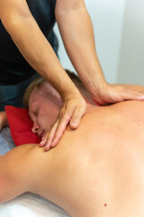 Physiotherapist doing a physiotherapeutic massage to the client on the back and neck with his hands