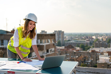 Portrait of engineer businesswoman at construction site. Female architect with blueprint.
