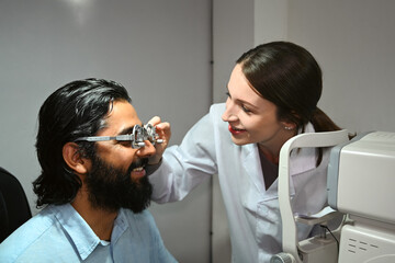 Female ophthalmologist testing vision or sight of girl patient for glasses or treatment in a clinic. Health care, medicine, eye sight concept