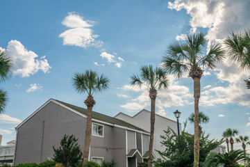 Bright white fluffy clouds in the sky above the residential buildings and palm trees at Destin, FL