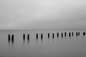 The ruins of an old pier sticking out of the water in Gdynia, Poland, in black and white