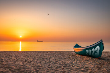 Happy new year 2023 relaxation morning on the beach concept. Fishing Boat and beautiful new sunrise or sunset on the seashore.