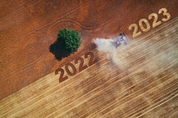 2023 Happy New Year agriculture concept. Aerial view on the combine working on the large wheat field