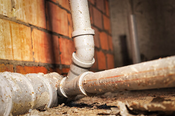 Sewer pipes in home basement. System of gray sanitary pipes when building a house. Sewer...
