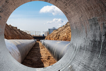 Modern water supply and sewerage system. Underground pipeline works. Water supply and wastewater disposal of a residential city. Close-up of underground utilities. View from the big pipe. - obrazy, fototapety, plakaty