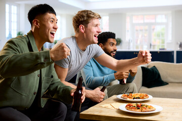 Group Of Excited Male Friends Watching Sports On TV At Home In Lounge With Pizza Together