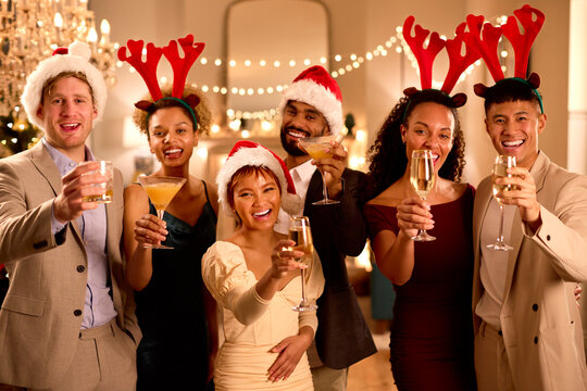 Portrait Of Friends Wearing Santa Hats And Reindeer Antlers At Christmas Or New Year Party