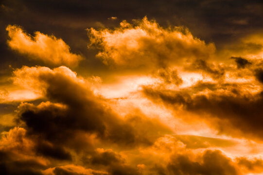 Die untergehende Sonne strahlt mit orangenem Licht durch eine aufbrechende Wolkendecke mit Wolkenfetzen
