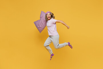 Full body young happy woman she wear purple pyjamas jam sleep eye mask rest relax at home jump high...