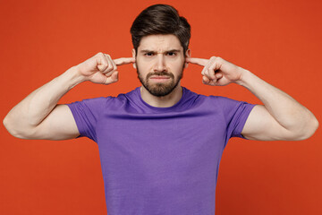 Fototapeta na wymiar Young dissatisfied annoyed caucasian man wears casual basic purple t-shirt closed eyes cover ears with hands fingers do not want to listen scream isolated on plain orange background studio portrait.