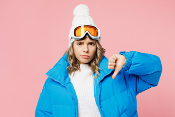 Snowboarder woman wear blue suit goggles mask hat ski padded jacket showing thumb down dislike gesture isolated on plain pastel pink background. Winter extreme sport hobby weekend trip relax concept.