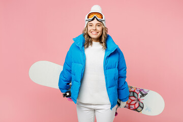 Snowboarder happy woman wear blue suit goggles mask hat ski padded jacket hold snowboard behind herself isolated on plain pastel pink background. Winter extreme sport hobby weekend trip relax concept.
