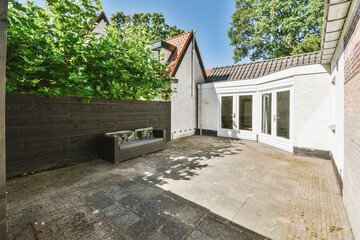 Neat paved patio with sitting area and small garden near wooden fence