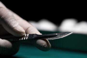Nurse hand taking surgical instrument for group of surgeons at background operating patient in...