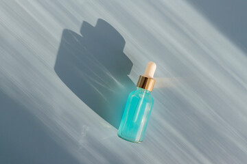 Cosmetic spa medical skincare, glass serum bottle with collagen on blue background with shadows. medical product adverticement for anti-aging care with marine ingredients