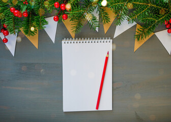 Top view of Christmas background with blank open notepad, pencil and christmas decorations