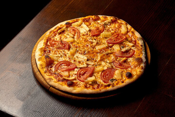 Italian Hawaiian pizza with chicken and pineapple on a wooden board. Italian cuisine. Close-up