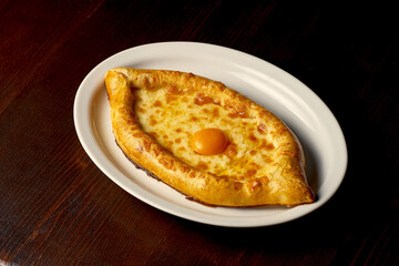 Traditional Adjarian khachapuri. Pie with cottage cheese and salty cheese in a plate. Georgian pastries