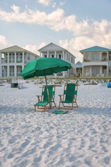 Destin, Florida- Green outdoor lounge chairs under the umbrella on a white beach sand