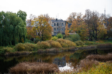 Fototapeta premium autumn landscape, old buildings along the river bank, Bauska, Latvia