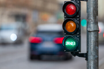 view of city traffic with traffic lights, in the foreground a semaphore with a green light, closeup