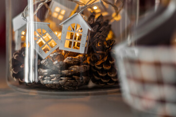 Pine cones in a glass jar and a garland of houses, a basket of nuts.