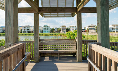 Destin, Florida- Shed on a boardwalk with seat against the lakefront houses at the back