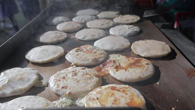 Pupusas a traditional salvadoran food being cooked in hot griddle close up.