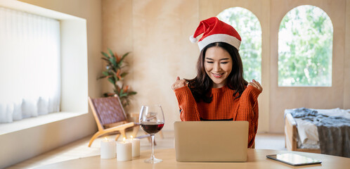 Portrait of beautiful business asian woman online working in bedroom desk use computer. Freelance online marketing ,girl video call on laptop toasting with wine celebrating succuess. Christmas alone