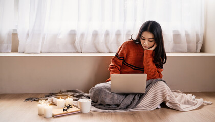 Asian nerd glasses woman work with computer cell phone on the floor. Warm woolen sweater in cold...