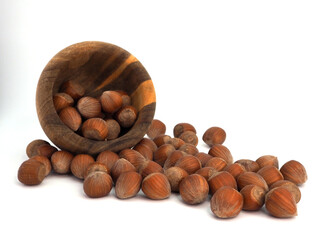 Hazelnuts spilled out of a wooden bowl