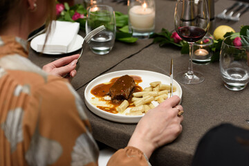 Woman eating pasticada with gnocchi, beef stew in a sauce. Croatian cuisine