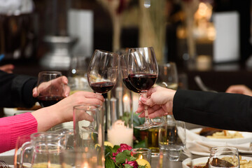 People hold in hands glasses with red wine. wedding party. friends toasting with a wine above table