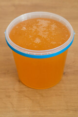Plastic bucket of honey on wooden table. Package. Honey in plastic bucket. Healthy food concept.