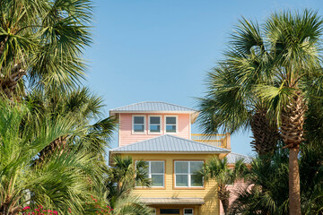 Fototapeta na wymiar Three-storey house with pastel pink and yellow painted wood siding in Destin, Florida