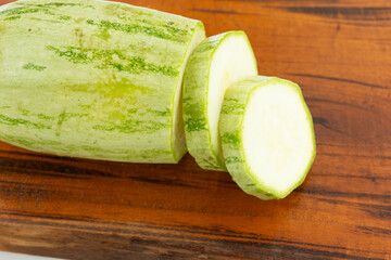 sliced fresh green cucumber on wooden cutting board