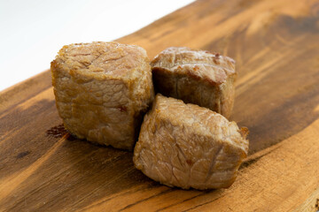 fresh baked meat cubes on a wooden board