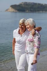Fototapeta na wymiar coppia di signore anziane abbraccia affettuosamente sulla riva del mare