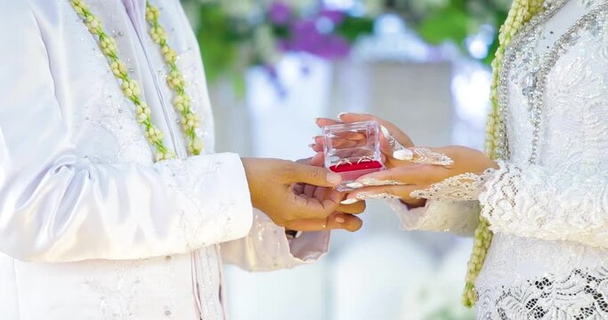 The dowry that the groom gave to the bride. Declaration of love at Indonesian weddings. Close up of loving male holding small box with diamond ring in hand presenting it to beloved young female