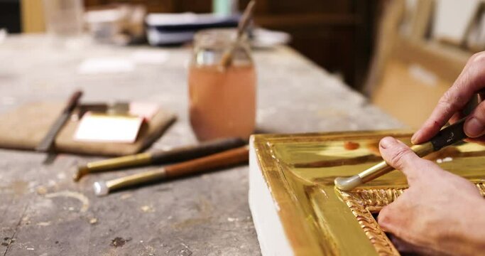 Hand of frame mker polishing gilded frame with agate