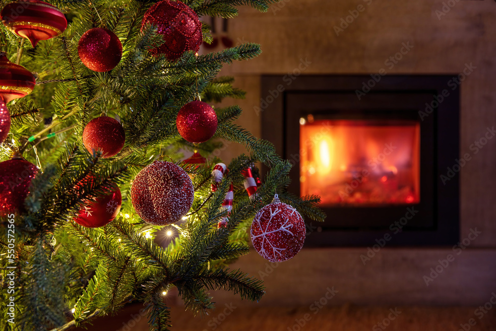 Wall mural christmas tree decoration and lights close up view, burning fireplace background.