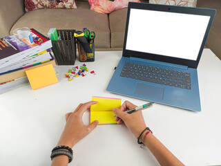 mockup image, Laptop computer with blank screen with a woman taking notes on yellow paper with pen in modern home room. mockups laptop