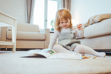 Shot of an adorable little girl doing arts and crafts. Creative little girl enjoying in time at home and drawing. Copy space. Small girl drawing at living room with colorful pencils
