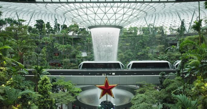 Airport train pass iconic rain vortex waterfall in Singapore rainforest; static